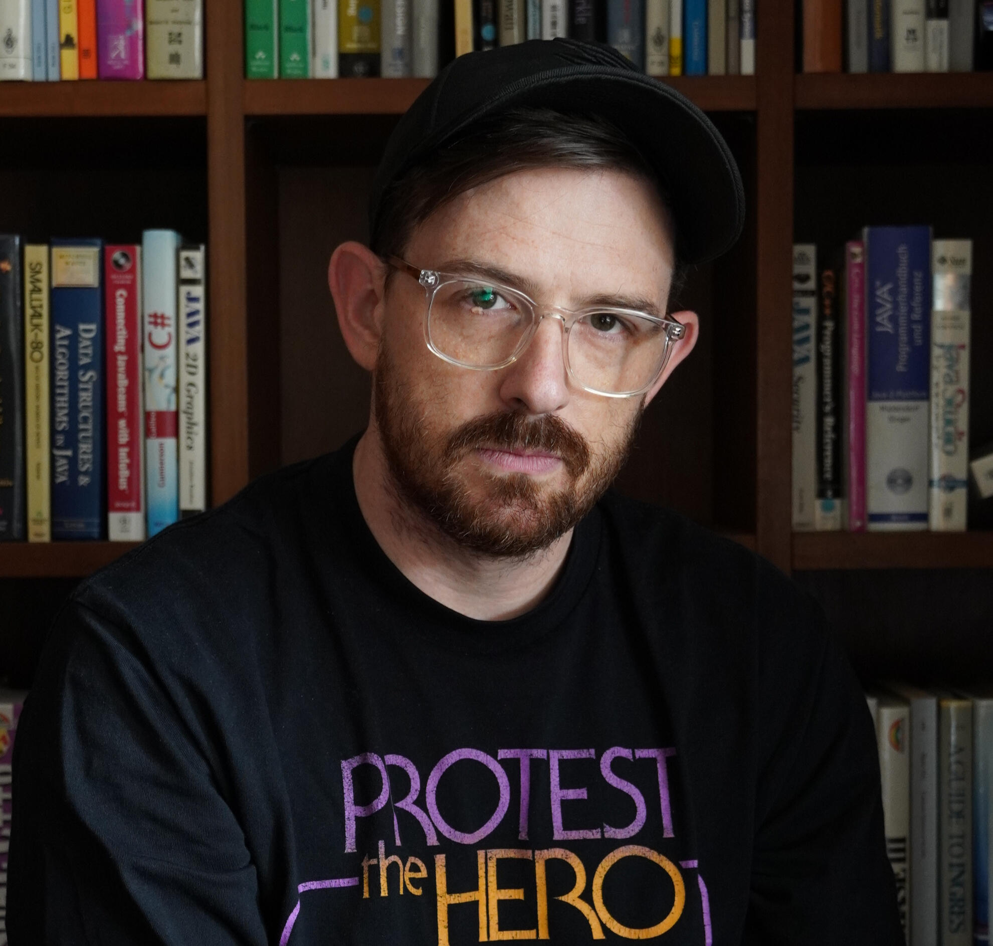 Jackson Ryan, Journalist An image of Jackson Ryan wearing a Protest the Hero long-sleeve black T-shirt and a black cap.
